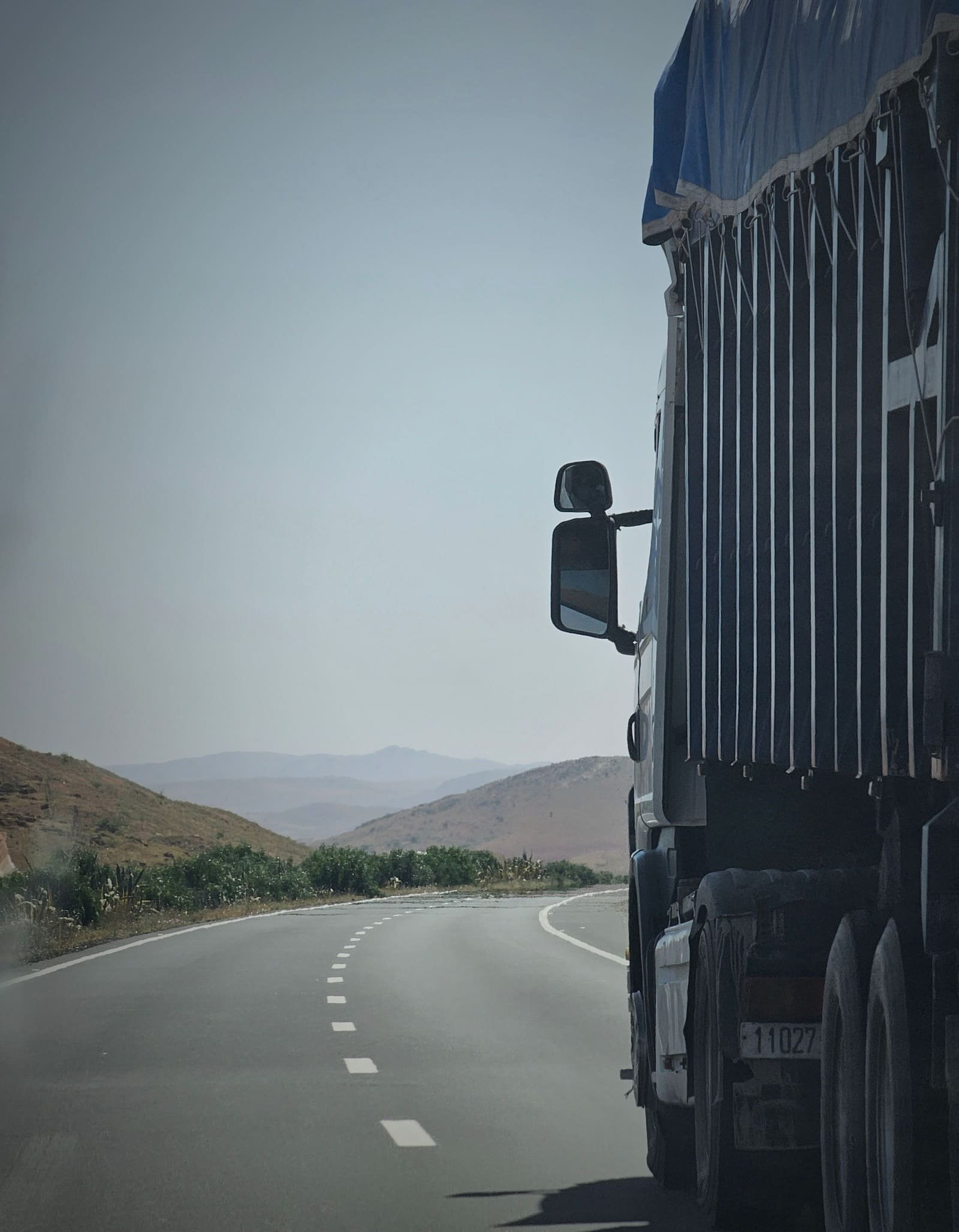 Freight truck driving along a highway through mountainous terrain